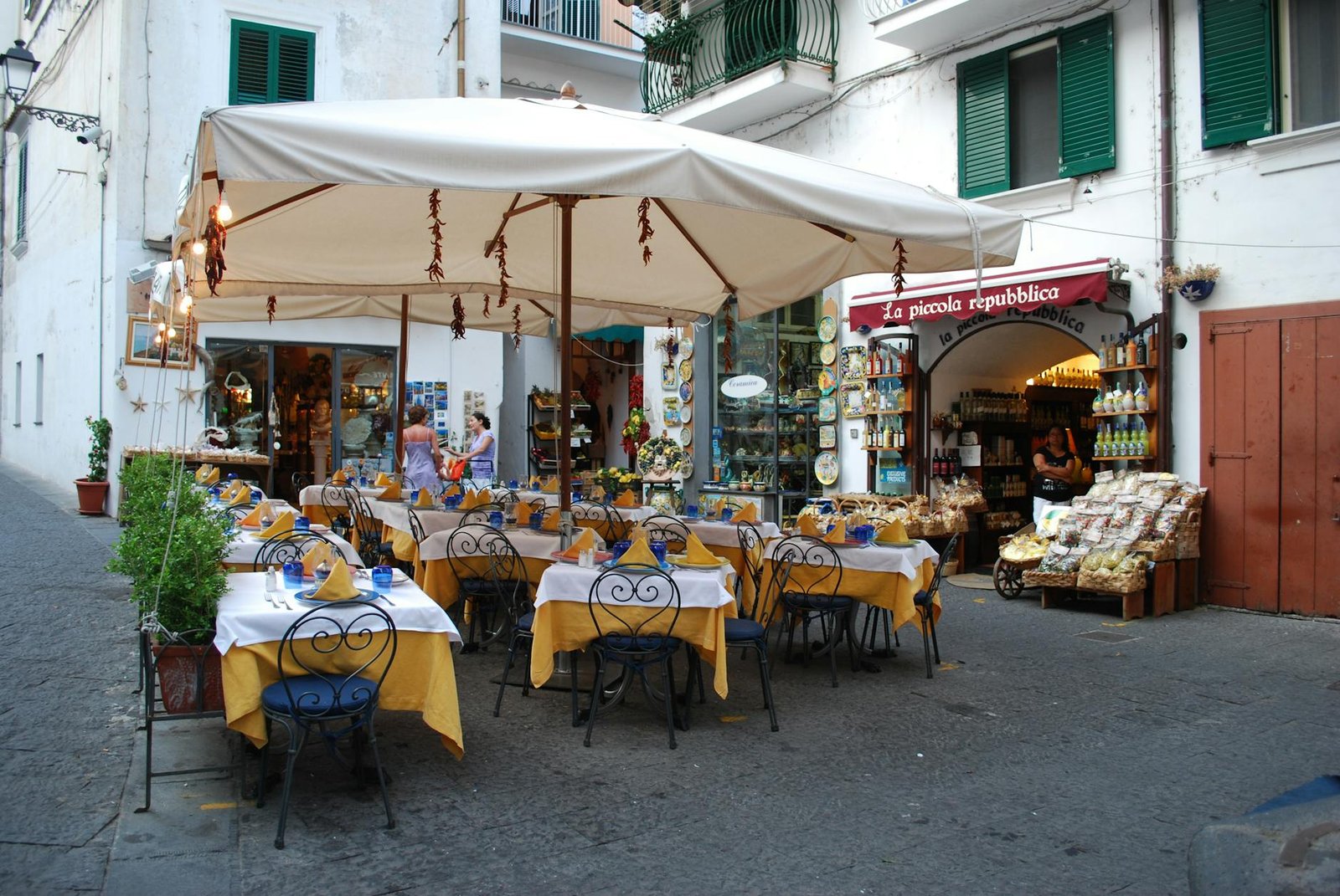 Picture of an outdoor café in the Amalfi Coast, Italy with tables, chairs, and umbrellas setting a vacation vibe.