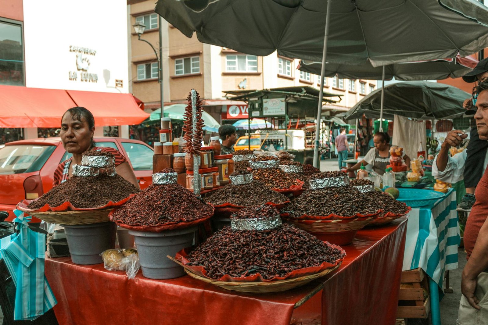Street market stall displaying an array of dried chilies and spices in an urban setting.