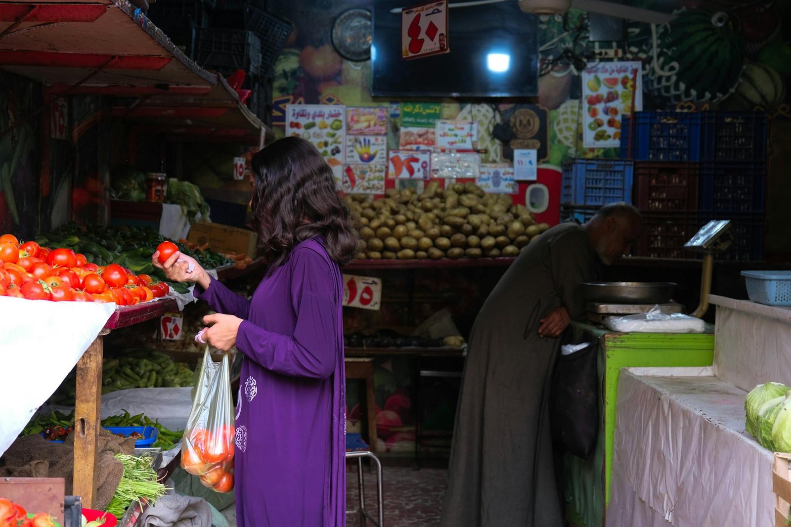 A woman shops for fresh produce in a vibrant Cairo market. Traditional market setting with colorful vegetables.