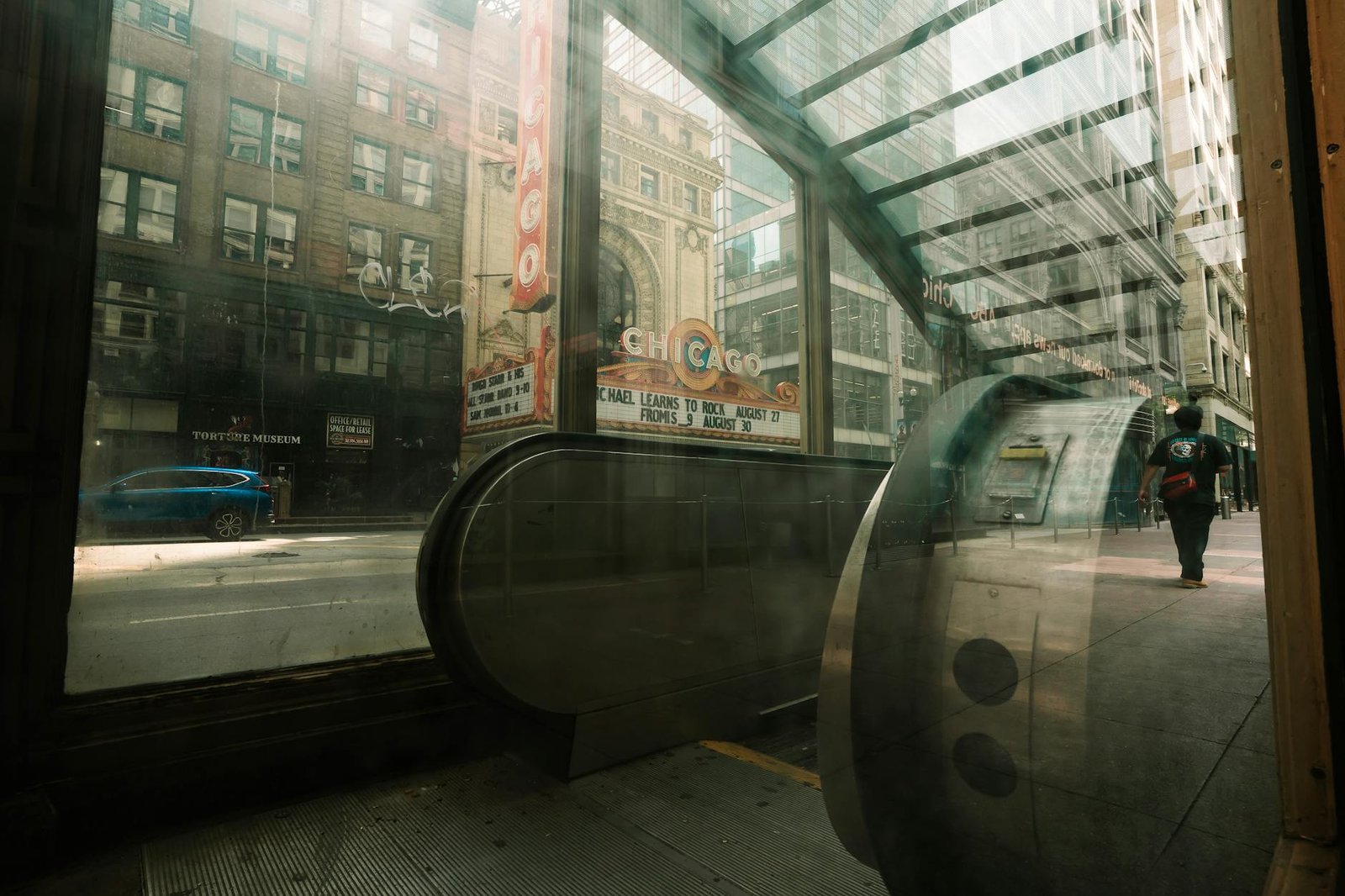 View of the iconic Chicago Theater marquee through an escalator entrance. Urban cityscape with reflections.