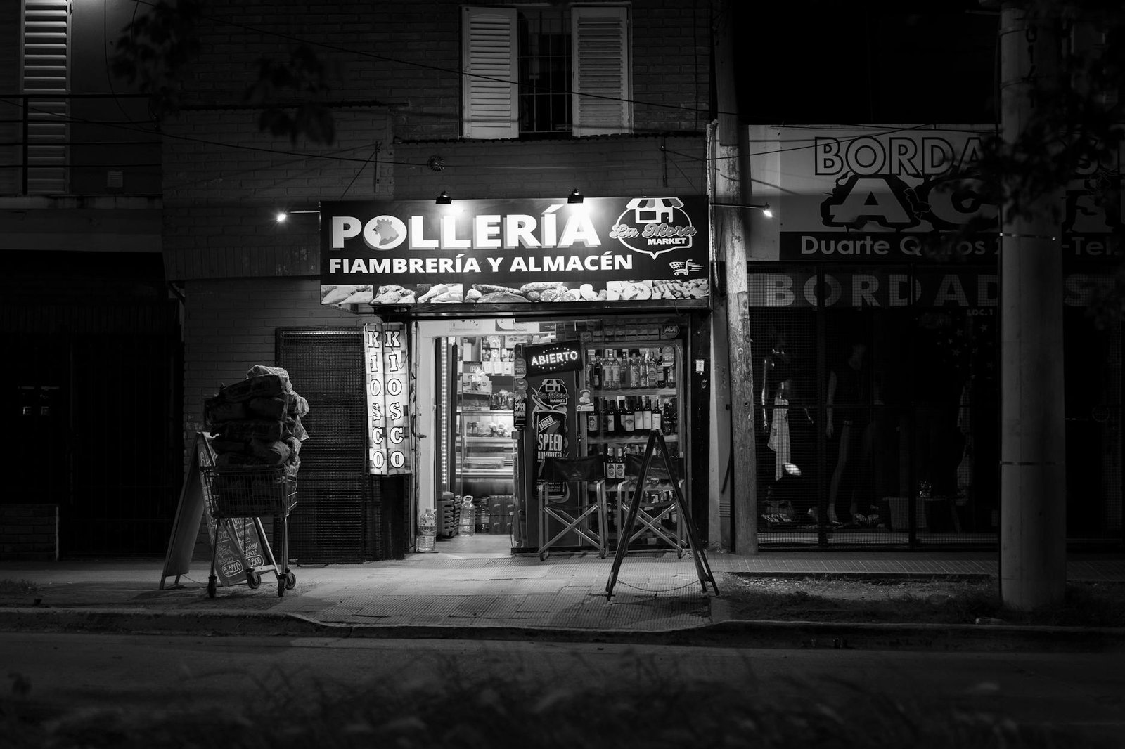 Black and white photo of a chicken shop at night in Córdoba, Argentina, showcasing urban nightlife.