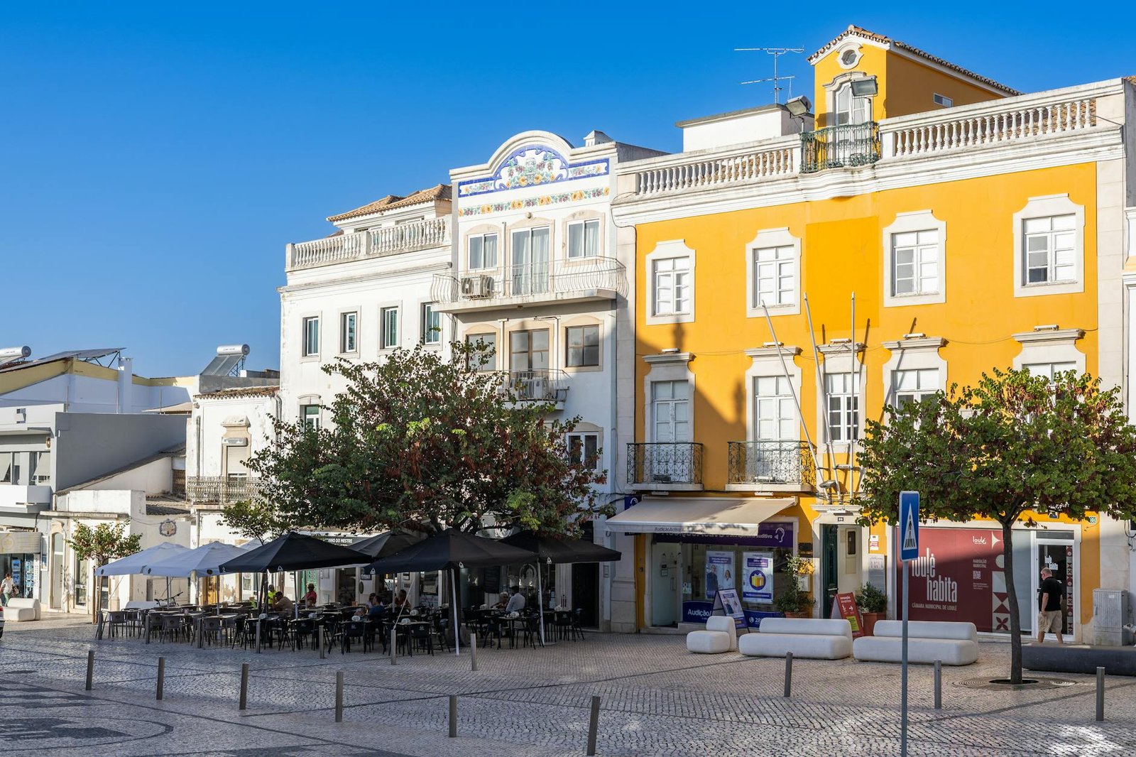 Explore the vibrant architecture and inviting outdoor cafes in a picturesque square in Loulé, Faro, Portugal.