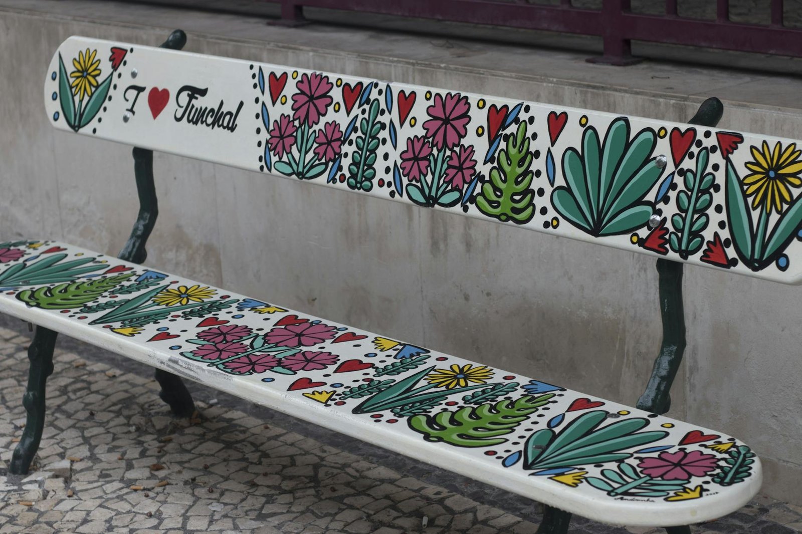 Vibrant decorated bench in Funchal, Madeira with floral designs and 'I Love Funchal' text.