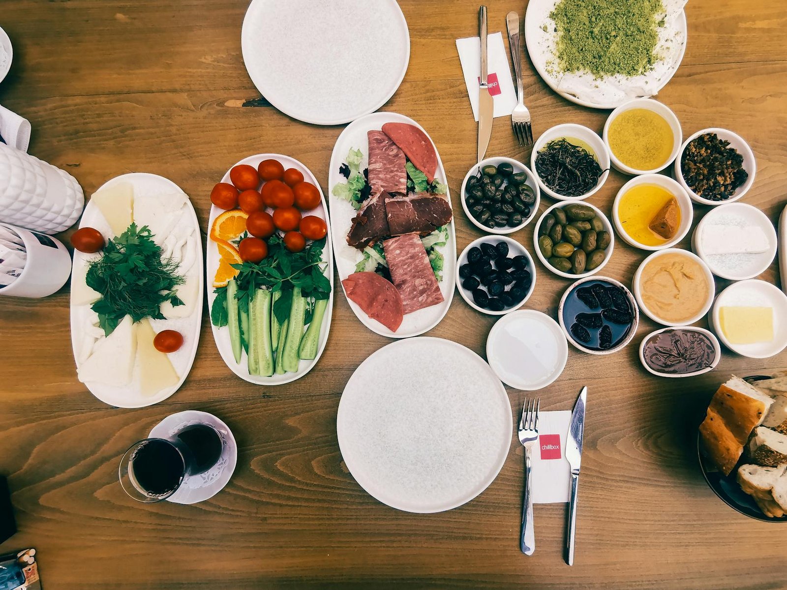 Delicious variety of Turkish breakfast dishes and meze, featuring fresh vegetables, cured meats, and olives.
