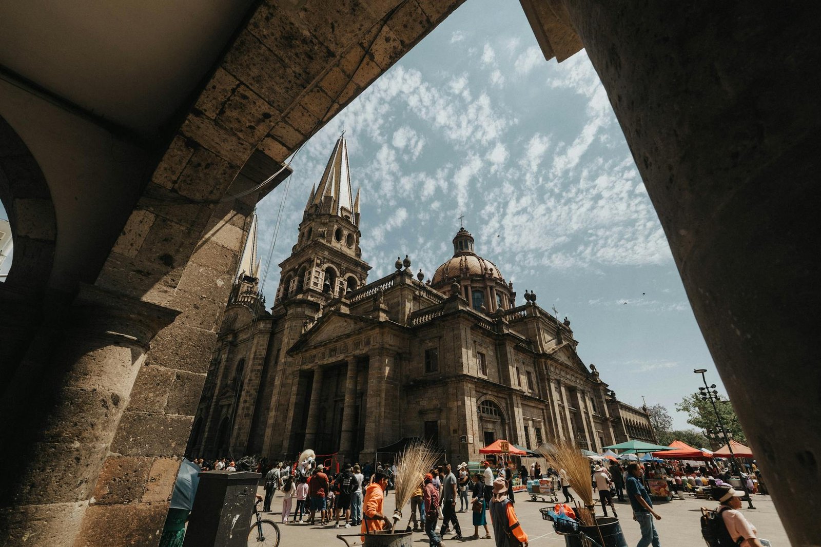 Captured under the archway, this photo showcases the stunning architecture of Guadalajara Cathedral with a lively public square.