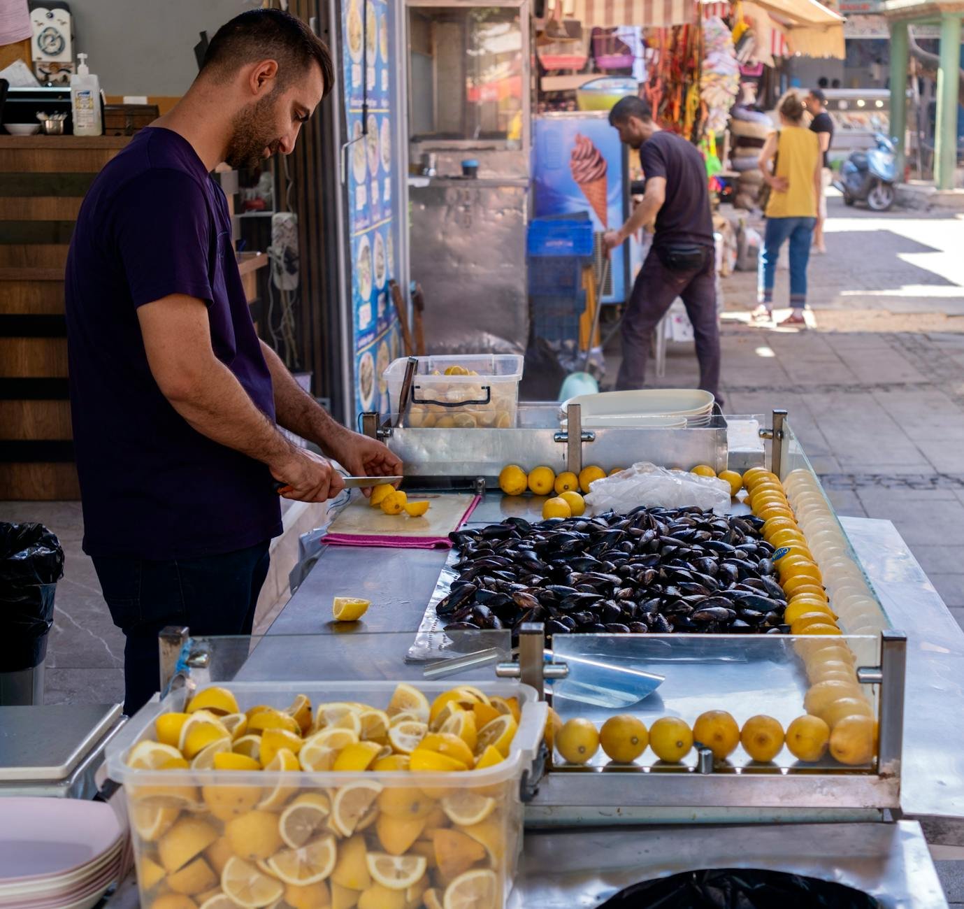 Street vendor slicing lemons and arranging mussels in İzmir, Türkiye.