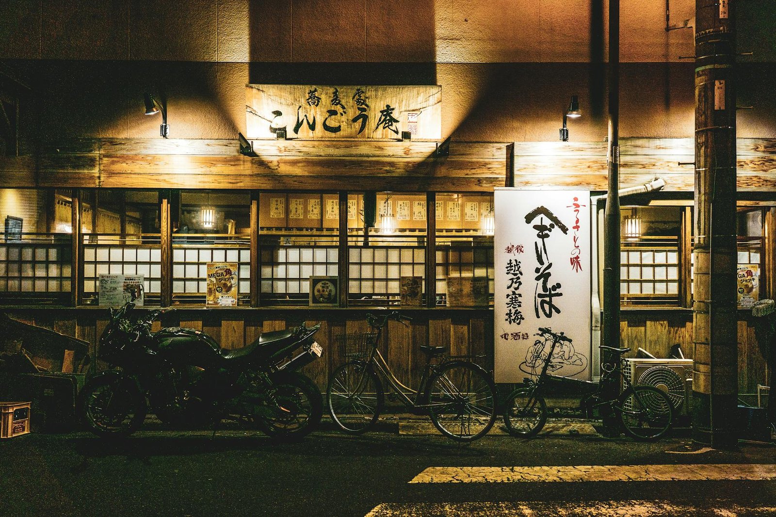 Illuminated Japanese restaurant facade with parked bicycles at night, showcasing authentic cultural elements.