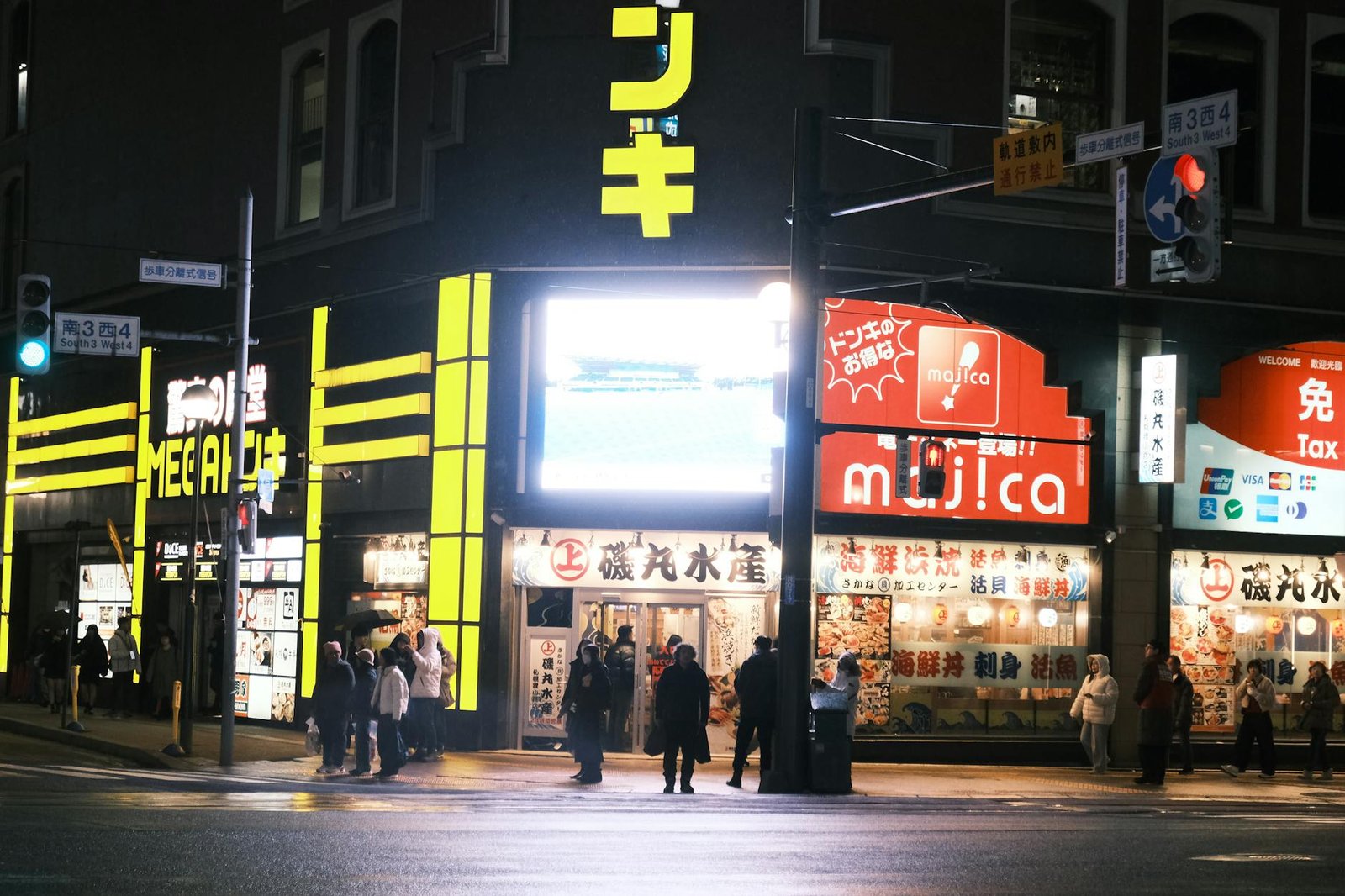 Bustling street scene in Sapporo, Hokkaido, showcasing vibrant store signs at night.