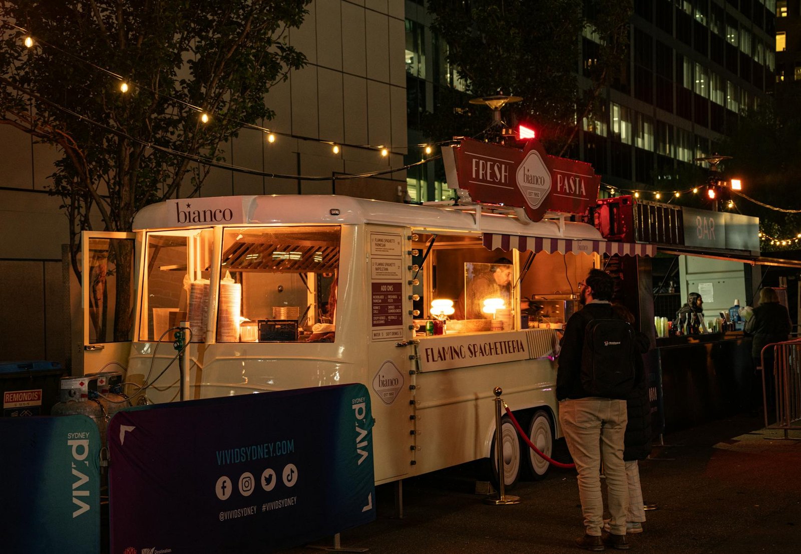 A vibrant food truck serving pasta at night during Vivid Sydney festival.