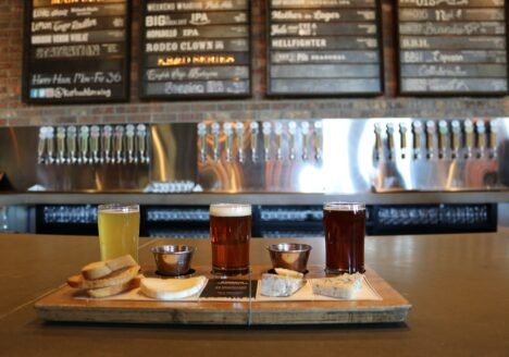 A selection of craft beers served with cheese and bread on a bar counter.