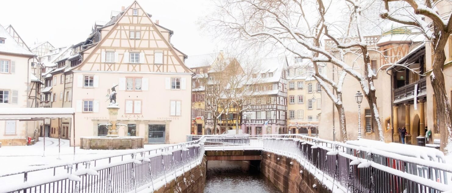 Snow along a canal in the old town of Colmar with half-timbered houses