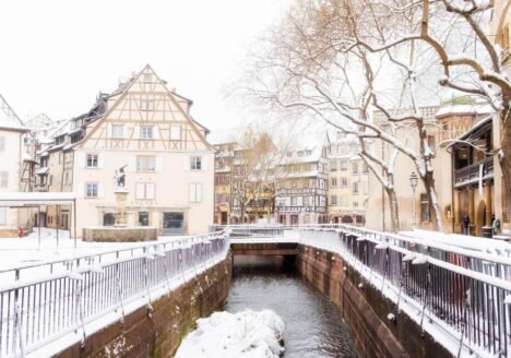 Snow along a canal in the old town of Colmar with half-timbered houses