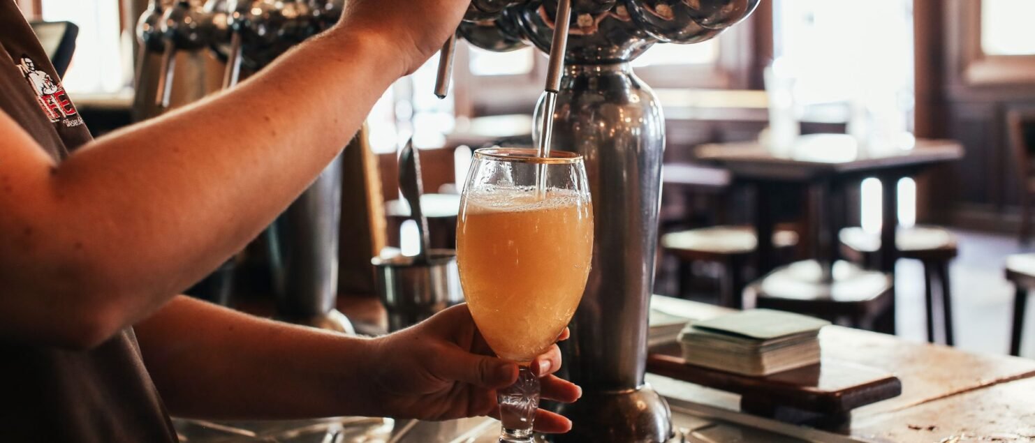 Bartender pouring a draft beer from a tap at a pub bar counter