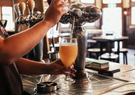 Bartender pouring a draft beer from a tap at a pub bar counter