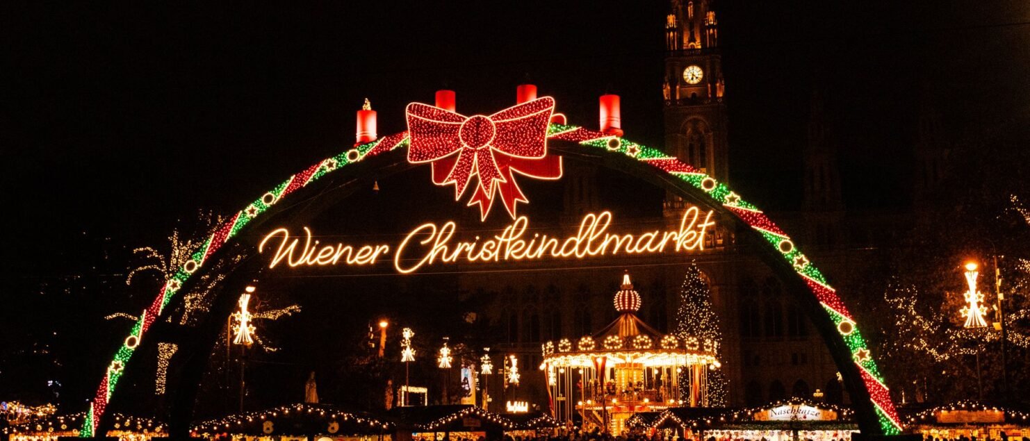 Illuminated Christmas market entrance arch at night in Vienna